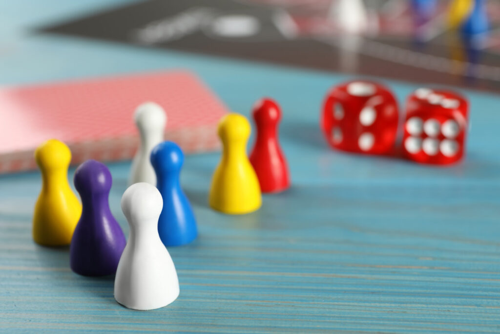 Closeup view of pawns and dices on light blue wooden table, space for text. Board game